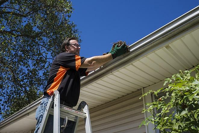 skilled worker repairing damaged gutter with tools in Piscataway NJ